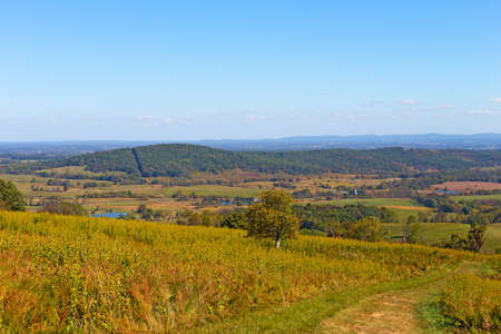 Countryside panorama with grassy fields, ponds and mountains on horizon. Autumn landscape with path through the field in Virginia, USA.の写真素材