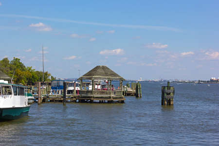 A pier at waterfront of Old Town Alexandria, Virginia, USA. A wooden gazebo and views over the Potomac River with US capital on horizon.の写真素材