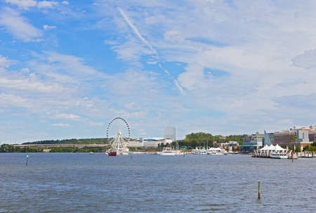 OXON HILL, MARYLAND, USA â SEPTEMBER 11, 2016: A view on the National Harbor and Potomac River waters. Panorama with boats, modern buildings and the Harbor Ferris under high skies with clouds.のeditorial素材