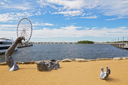 OXON HILL, MARYLAND, USA â SEPTEMBER 11, 2016: Awakening Sculpture of National Harbor on a sandy beach. The giant sculpture with a view on Ferris and Woodrow Wilson bridge.のeditorial素材