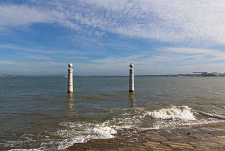 A view on Tagus River and Columns Pier at sunset in Lisbon, Portugal. Cumulus in the sky and white foam waves at the pier.の写真素材