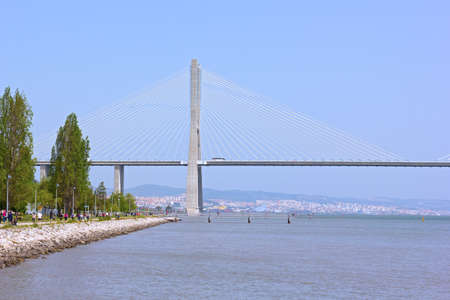 LISBON, PORTUGAL â APRIL 25, 2018: The first support of the Vasco da Gama bridge and pedestrian walkway along the river with the capital city on horizon.のeditorial素材