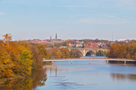 A view on suburban Washington DC in autumn with university buildings and bridges across Potomac River. Urban landscape on early morning with reflection in quiet river waters, Washington DC, USA.の写真素材