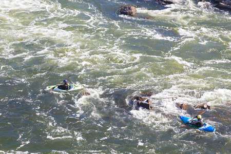 Kayaking on rapids of Potomac River in Great Fall Park in Virginia, USA. A view on kayakers from the top of Great Falls canyon.のeditorial素材