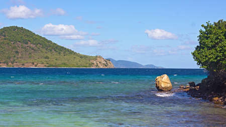 Tropical island landscape with sea view and several mountainous islands on horizon, St. Thomas, Virgin Islands US. Gentle waves and rocky shoreline of the island.の写真素材