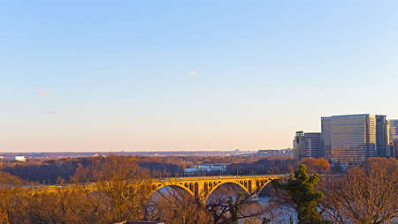 Washington DC suburban panorama along Potomac River in winter, USA. Key Bridge and Arlington skyscrapers in city landscape at sunset.の写真素材