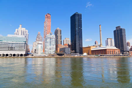 Manhattan skyline in the morning near East River waterfront in New York, USA. Urban landscape with river view and bright blue skies.の写真素材