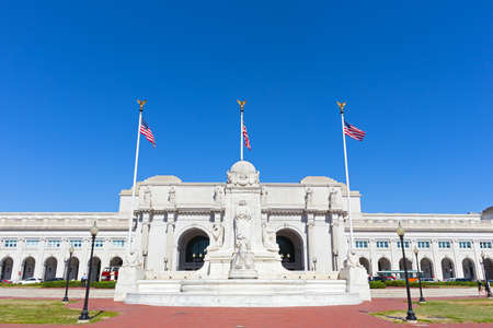 A square in front of the Union Station Building in Washington DC, USA. Monument and marble statues of the station building in harmony with three national flags at the busy transportation hub of US capital city.の写真素材