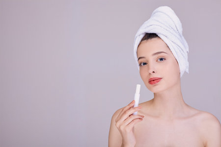 Portrait of a pretty young lady applying lip balm on the background. Girl after a shower in a white...
