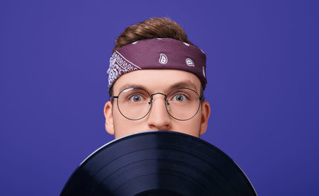 An astonished guy with round glasses, a striped T-shirt, a bandana on a head covered his face with a...