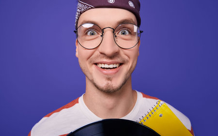 A happy funny guy in round glasses and a brown bandana on his head is very surprised and looks...