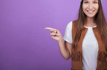 Cropped frame. A brown-haired woman with green eyes in a white T-shirt points to the side with the index finger of her left hand. Style 90.の写真素材