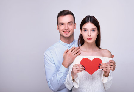 Charming couple madly in love. A nice smiling guy hugs with both hands beautiful girl in a snowy...