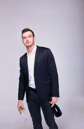 Full length of a smiling handsome young businessman standing and holding a glass of champagne on a white background.の写真素材
