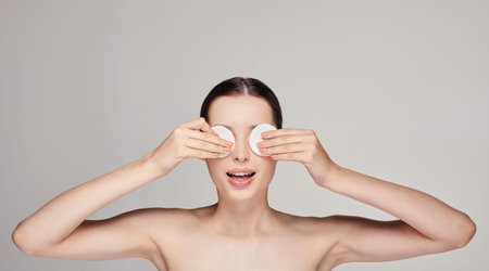 Wellness, body care. Close-up young beautiful surprised girl with cotton pads in both hands near the...