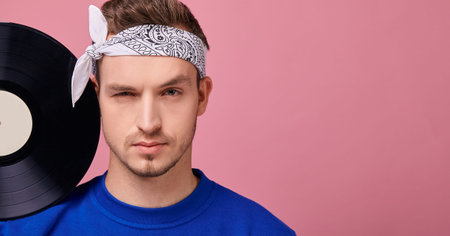 The average plan. A cool stylish guy in a bandana in a dark blue jacket stands on a pink background...