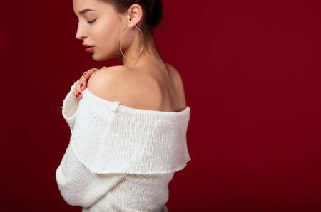 The cropped frame of the girl with dark hair and radiant white skin closed her eyes, touches her shoulder and stands half-sided. A female romantic image. The girl goes on a date.の写真素材