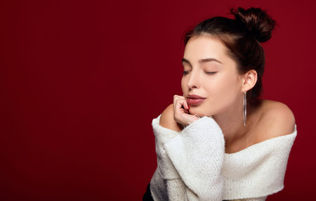 Close-up, the dreamy young brown-haired woman with plump lips and glowing white skin dreamily closed...