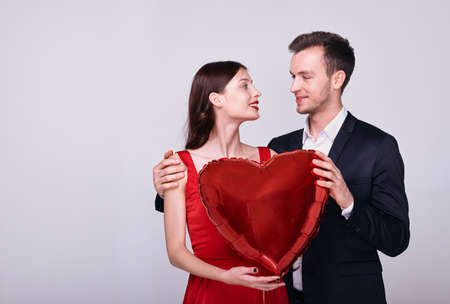 Headshot portrait young happy romantic loving couple looking at each other, girl put hand on mans shoulder isolated on grey white studio background. Dating, romantic relations concept. Copy space.の写真素材