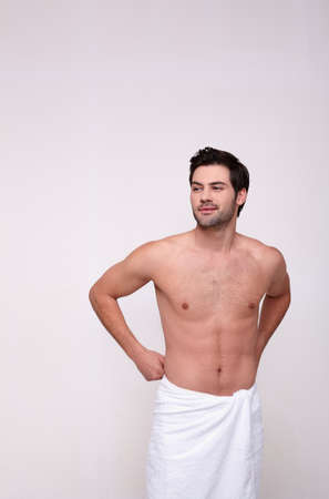 Beautiful naked muscular man looks to the side, posing on a white background. Caucasian brutal sexy man with a bare torso.の写真素材
