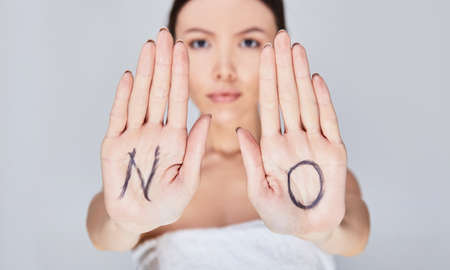 Close-up of the women's palms on which the word NO is written. The concept of feminism, freedom, women's rights.の写真素材