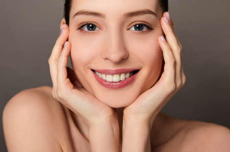 Beauty Woman face Portrait. Beautiful model Girl with Perfect Fresh Clean Skin tanned. Healthy teeth smile Youth and Skin Care Concept.の写真素材