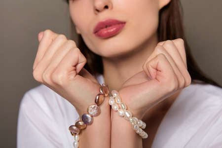 Close-up, a young beautiful white girl, holds her hands near her face, her wrists tied with pearl beads. The concept of natural cosmetics, the exclusive pearls.の写真素材