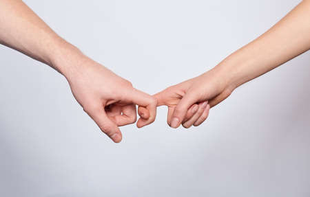 Close-up, two young white hands holding on to each other, poured against a white background. The concept of love, together forever, support.の写真素材