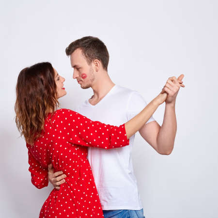 Long frame, young beautiful caucasian couple, he and she, in elegant clothes bonding and dancing, standing on a white background.の写真素材