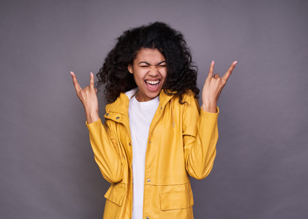 A young cute cheerful naughty girl African, with a curly hairdo, in a white T-shirt and a yellow...