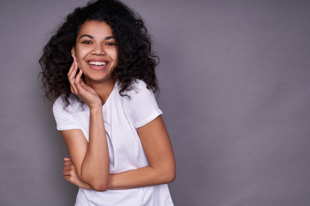 A cheerful African American with a pleasant smile, curly dark hair, healthy skin, wears a white...