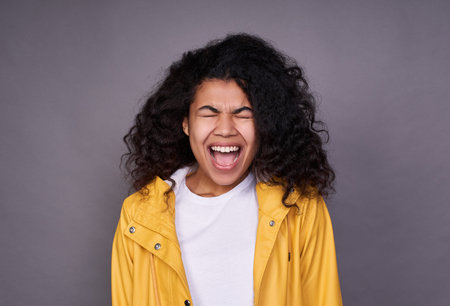 Young pretty funny, funny dark-skinned girl with a lush curly hair, in a white T-shirt and yellow...