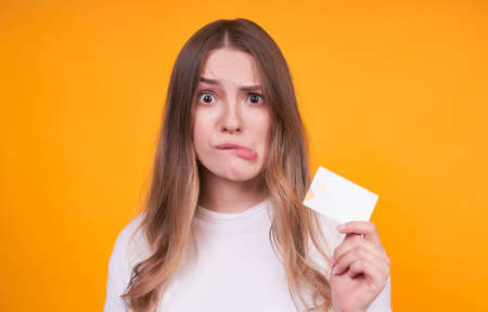 Portrait of a cute wild teenager, funny face of a blonde with a credit card, who does not understand where she spent the money, copi space.の写真素材