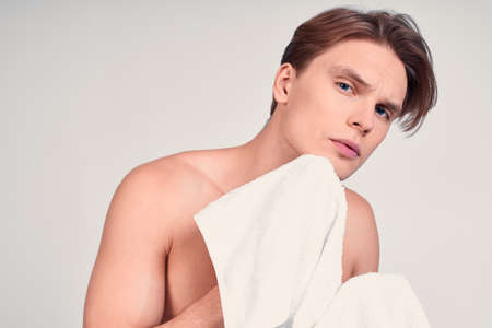 Surprised, shocked young naked man, a young man, blond with blue eyes, wears patches on his face to moisturize the skin, shocked by the effect of rejuvenation.の写真素材