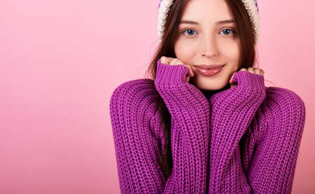 Beautiful Frenchwoman in a gentle blue beret, a striped blouse and a yellow rain jacket with glasses on a pink background. A lady makes a sign with her hands in her heart and shows love. Rainy day.の写真素材
