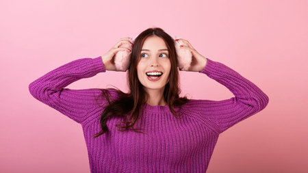 Lovely dark-haired lady in a knitted sweater.She smiles broadly and holds fluffy pink winter...
