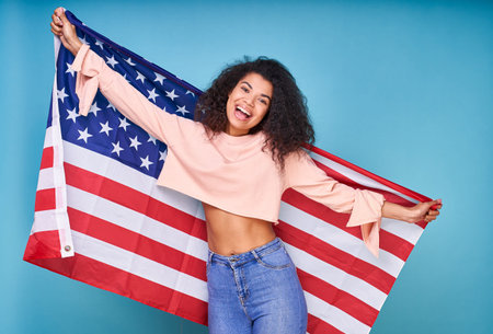 Cheerful attractive dark skinned ethnic emigrant woman, with curly hair, wears a beige sweater and...