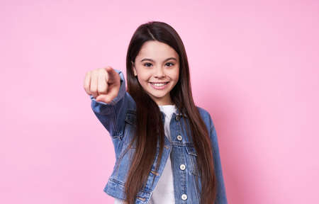 Young emotional child in a jeans jacket on a pink background.の写真素材