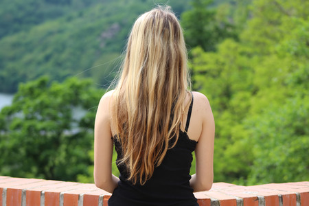 Young blond woman looking at the river. Concept of female beauty, rest in the nature. Rear view.の写真素材