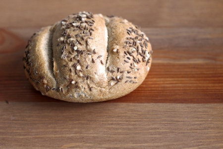 Fresh crusty bread roll with linseed and sunflower seed on wood background.Top view, copy space,...