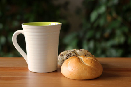 Breakfast with coffee and freshly baked poppy-seed kaiser bun on wooden table.Blurred background....