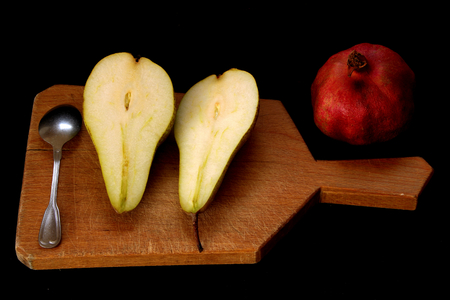 Fresh ripe organic yellow pears and pomegranate on wooden board on dark background. Vegetarian, vegan, healthy diet food. Selective focus.Food concept. Free space for text.の写真素材