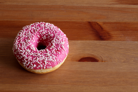 Donut with pink icing on a dark wooden background. Top view,food concept.の写真素材