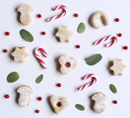 Christmas styled stock composition. Candy cane,homemade festive sweets and Eucalyptus leaves on white background. Flat lay, top view,winter decorative pattern.の写真素材