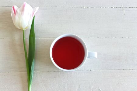 Romantic background with cup of tea and tulips on white table. Soft photo. Greeting card style, place for text, top view . Valentines composition.の写真素材