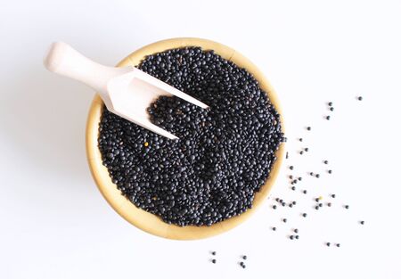 Heap of black organic beluga lentils with wood spoon in wooden bowl on white table background.Concept of food.Its black color even includes similar antioxidants like blueberries and blackberries.の写真素材