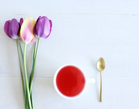 Romantic background with cup of tea and tulips on white table. Soft photo. Greeting card style, place for text. Top view,valentines composition.の写真素材