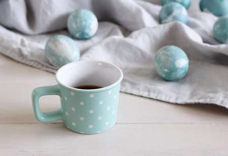Spring breakfast still life scene. Mug with coffee, Easter eggs on linen tablecloth. Easter food and...