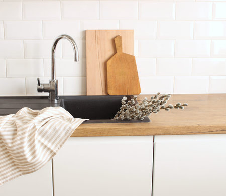 Closeup of kitchen interior. White brick wall, metro tiles, wooden countertops with chopping boards....