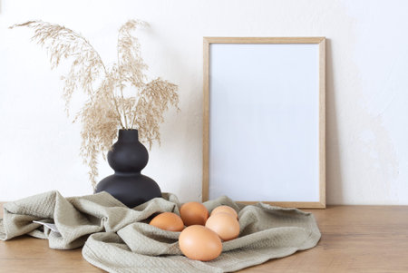 Spring, Easter still life. Empty picture frame mockups. Linen tablecloth, hen eggs. Reed grasses in...